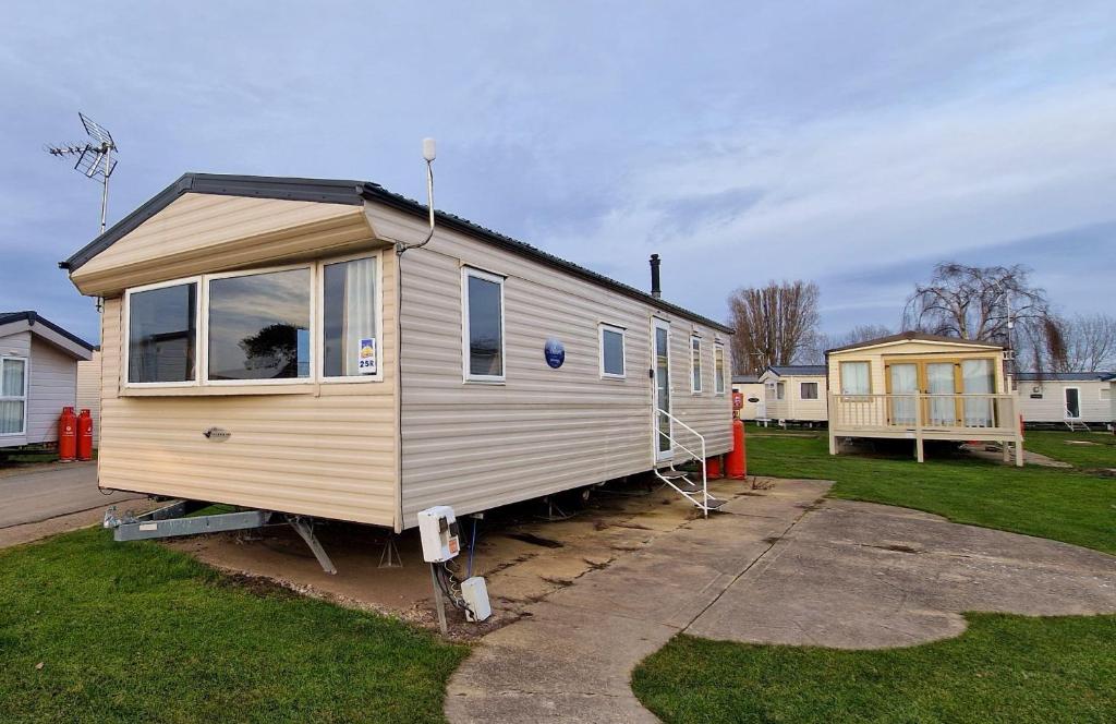 a tiny house is parked in a yard at 8 Berth Caravan With Wifi At Seawick Holiday Park Ref 27025r in Clacton-on-Sea