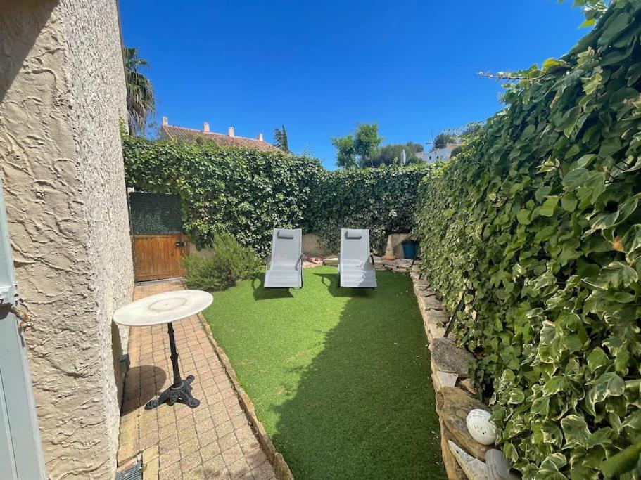 - un jardin avec deux chaises assises sur la pelouse dans l'établissement Appart-St Cyr sur Mer-La Madrague-4pers-Parking, à Saint-Cyr-sur-Mer