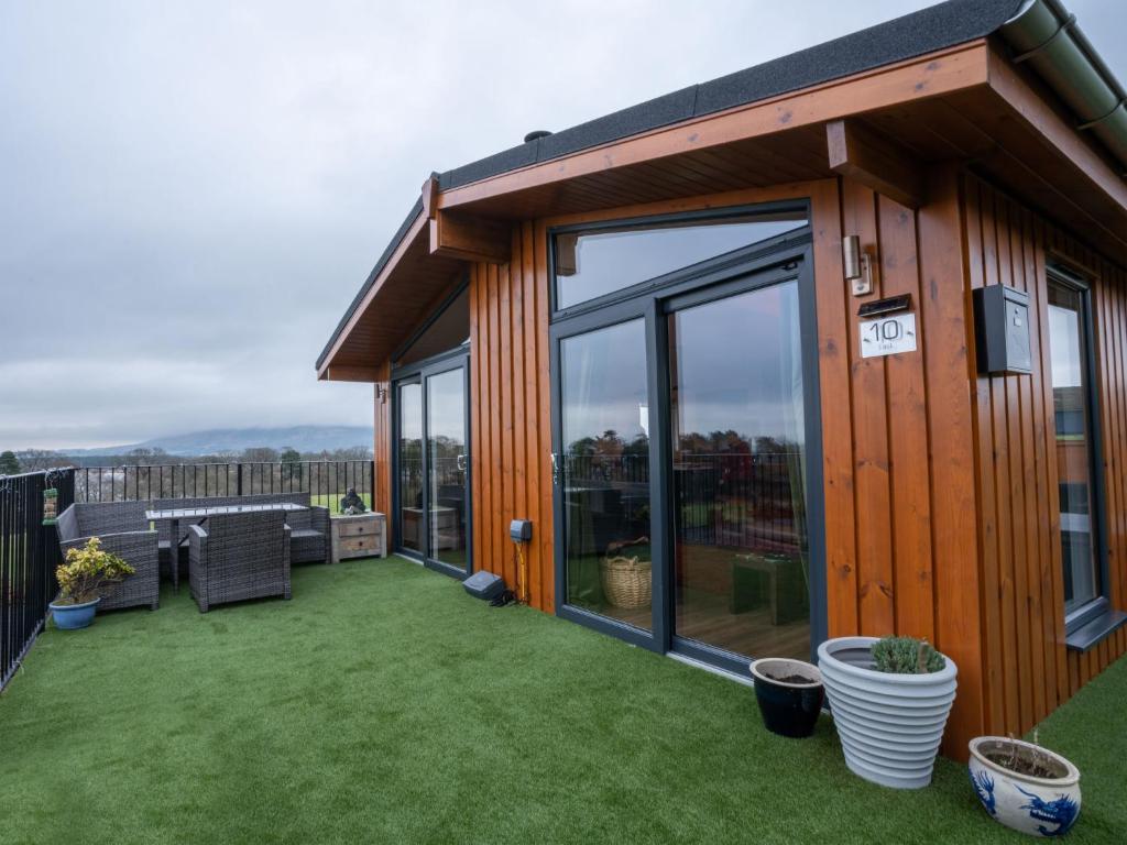 ein Haus mit einer großen Terrasse mit Gras in der Unterkunft Chalet Loch Leven Lodge 25 East by Interhome in Kinross