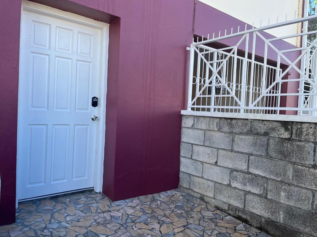 una puerta blanca junto a una pared púrpura en TETE Comforts, en Roseau