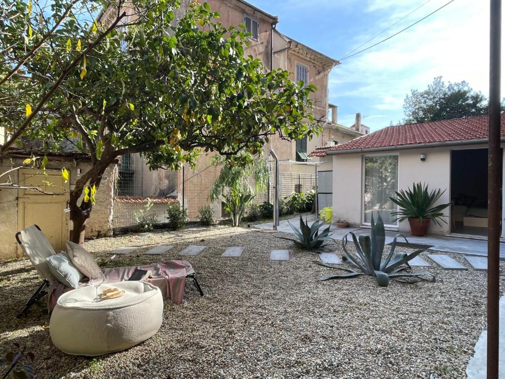 a courtyard with a tree and chairs and a house at Apartment La casa di Manu by Interhome in Porto Maurizio