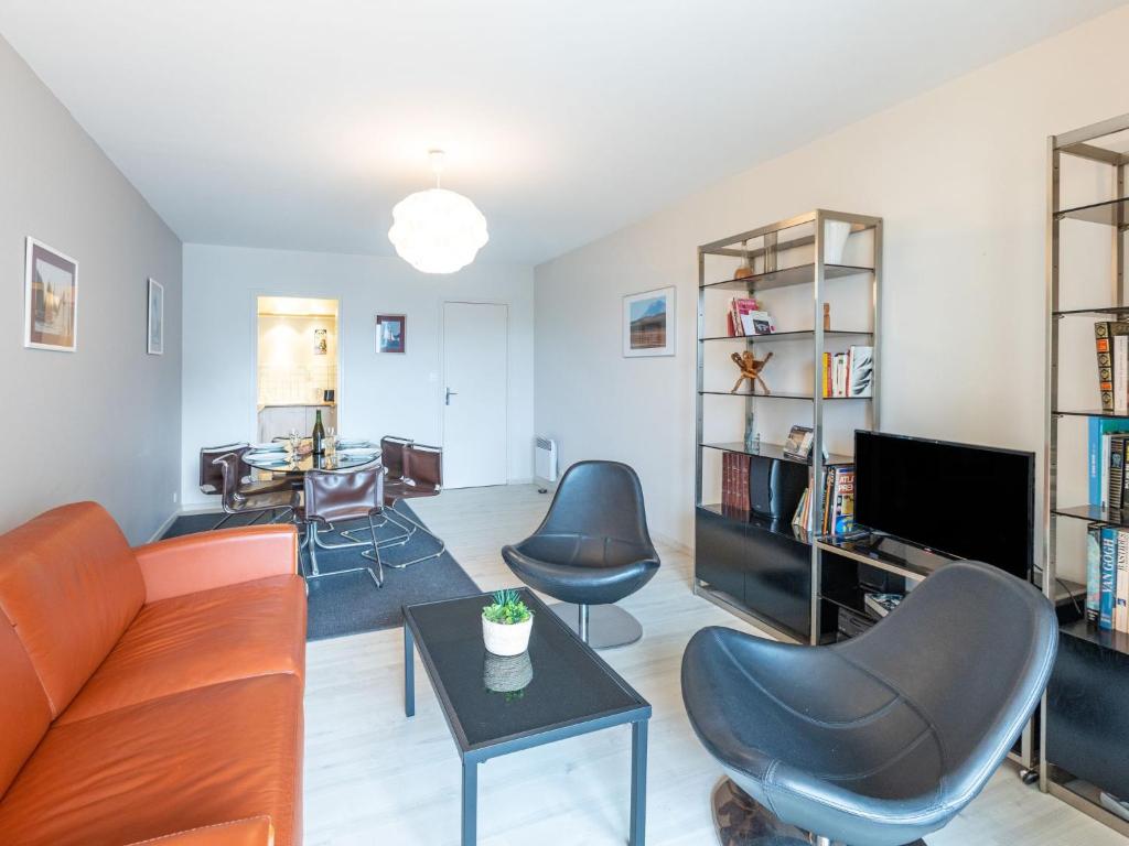 een woonkamer met een bank, stoelen en een tv bij Apartment Le Galion-2 by Interhome in Dinard