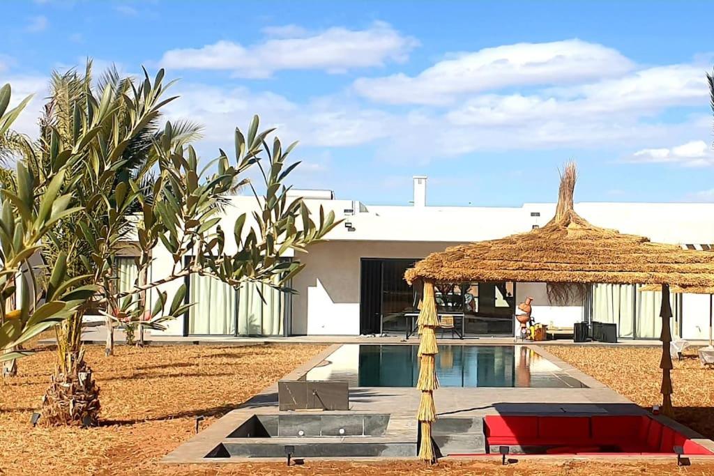 a house with a swimming pool and a straw umbrella at Villa Marrakech in Marrakesh