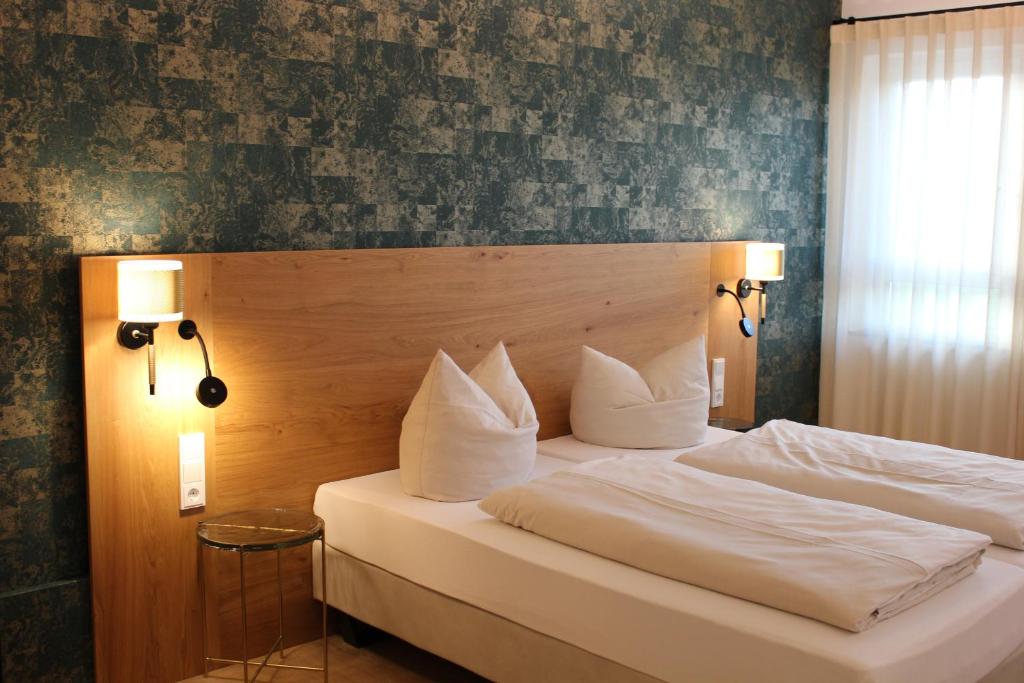 a bedroom with a bed with white sheets and pillows at Hotel Poellners 20 min von München Hbf in Petershausen