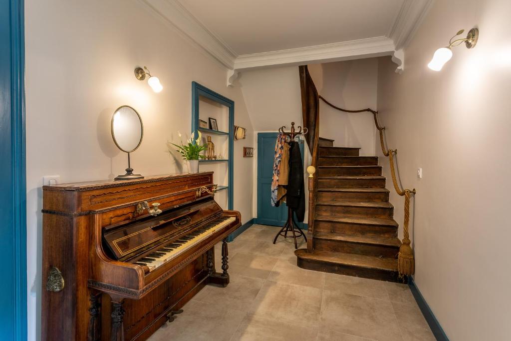 an old piano in a hallway with a staircase at Le Garage, Le Gite in Fontevraud-l'Abbaye