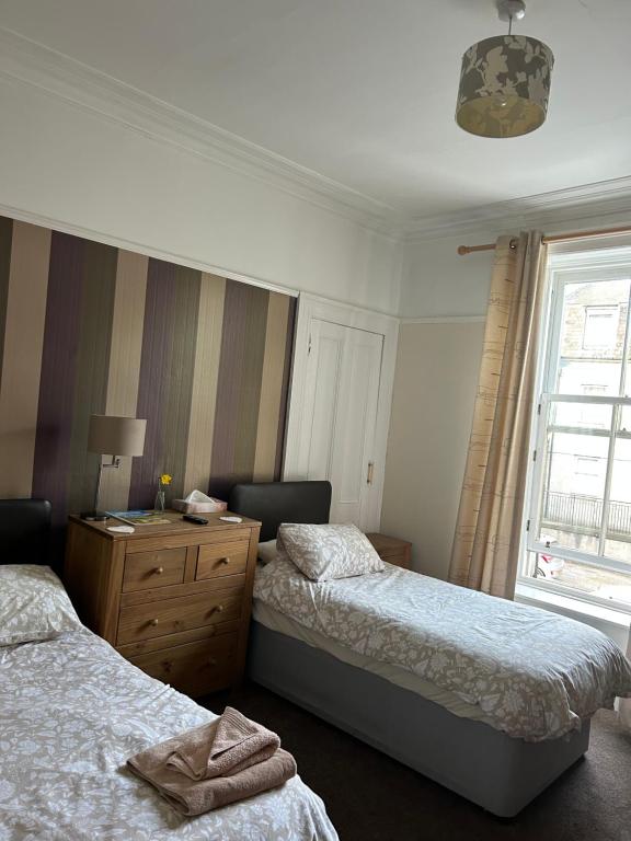 a bedroom with two beds and a dresser and a window at Roselodge Guest House in Aberdeen