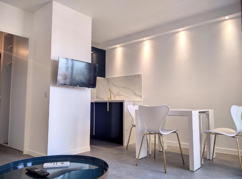 salon ze stołem, krzesłami i telewizorem w obiekcie Résidence Graziella Studio 411 w mieście Juan-les-Pins