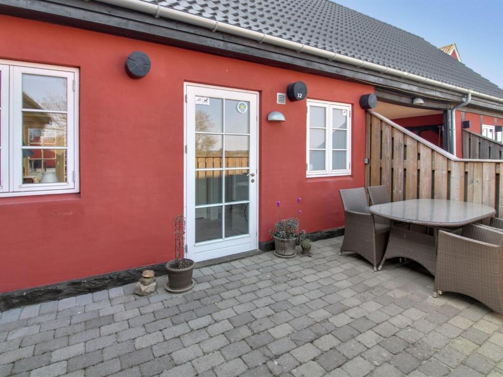 a red house with a patio with a table at Apartment Gisella - 6km from the sea in Bornholm by Interhome in Åkirkeby