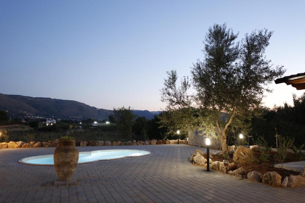 ein kreisförmiger Pool in einem steinernen Gehweg mit einem Baum in der Unterkunft Villa la Giara in Castellammare del Golfo