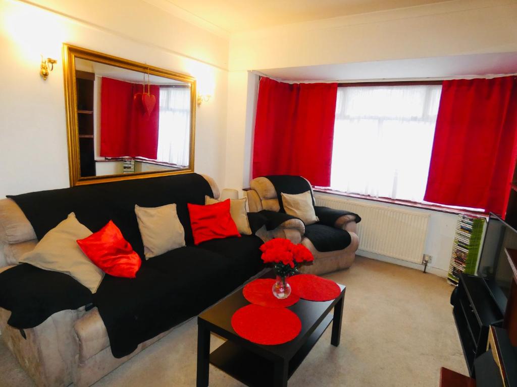 sala de estar con sofá negro y cortinas rojas en SPACIOUS 3 BED HOUSE WITH PARKING & GOOD TRANSPORT, en South Norwood