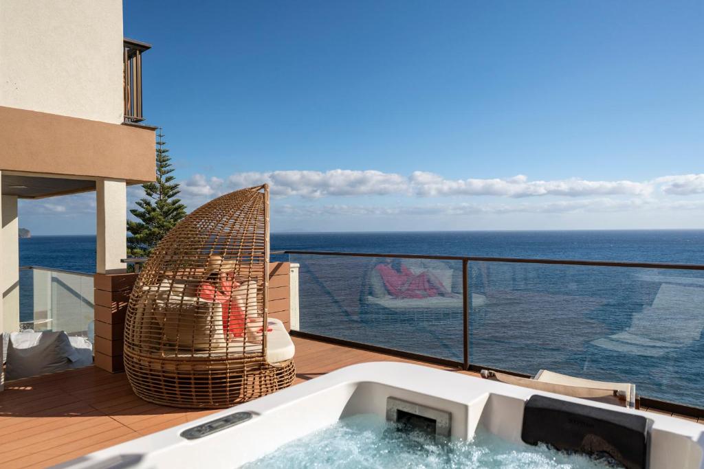 uma banheira de hidromassagem numa varanda com vista para o oceano em Baía I by An Island Apart no Funchal
