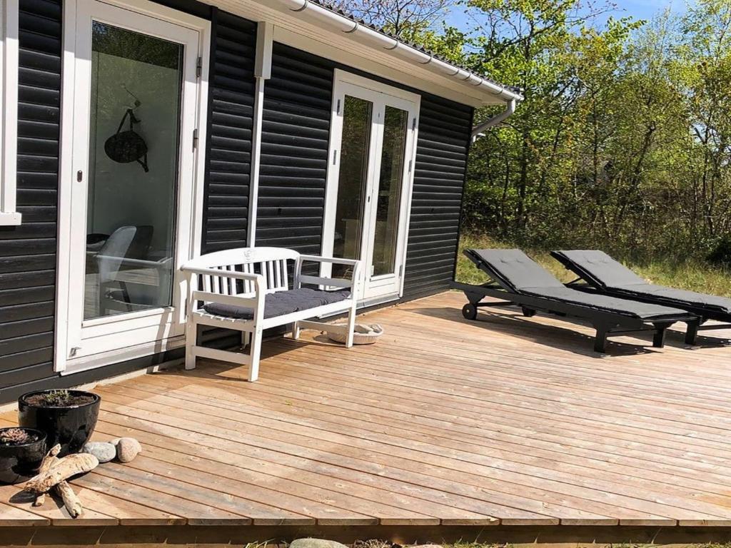 a wooden deck with two benches on a house at Holiday Home Aida - 400m from the sea in Bornholm by Interhome in Rønne