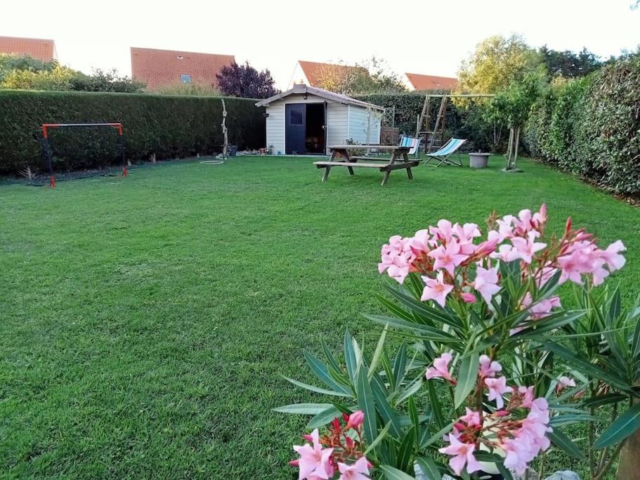 einen Garten mit einer Bank und rosa Blumen in der Unterkunft Soleil d'Opale et son grand jardin in Wimereux