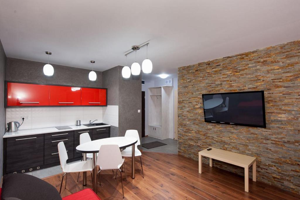 eine Küche mit einem Tisch und einem TV an einer Backsteinwand in der Unterkunft Apartament Mysia in Świeradów-Zdrój