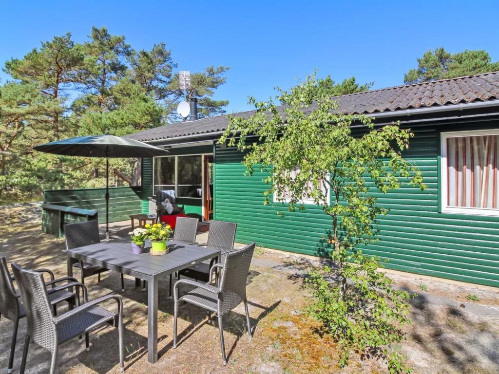 einen Tisch mit Stühlen und einen Regenschirm vor einem Haus in der Unterkunft Holiday Home Michel - 300m from the sea in Bornholm by Interhome in Vester Sømarken
