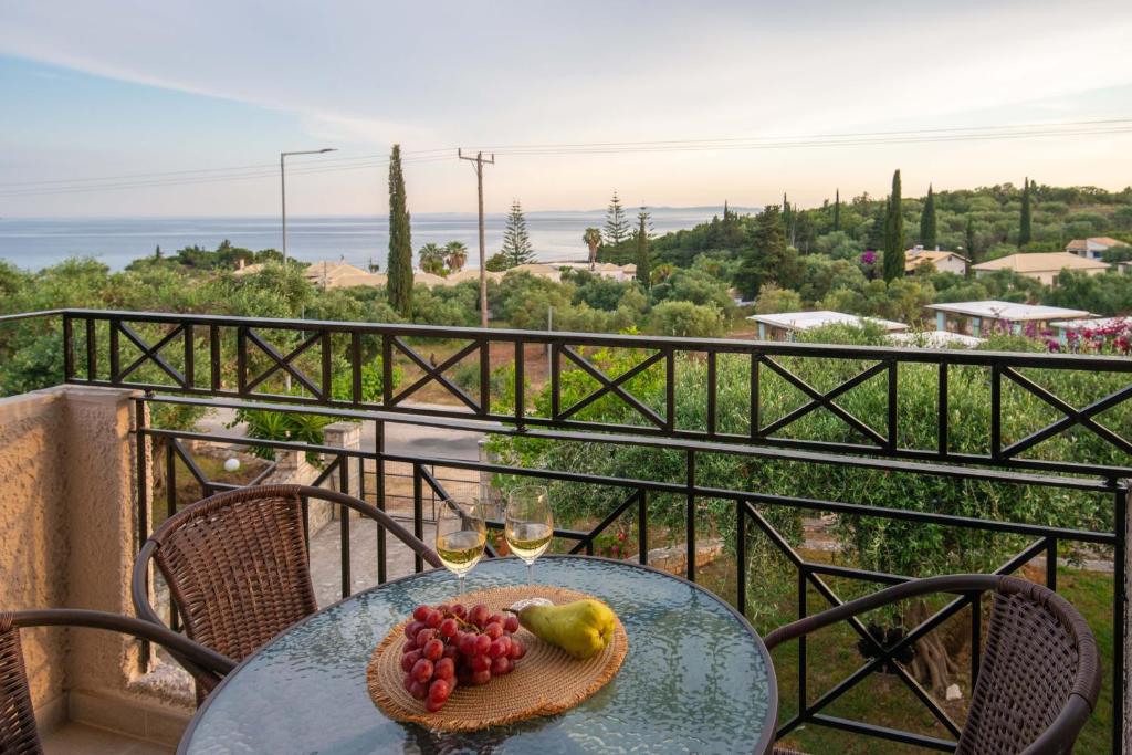 a table with a plate of fruit and wine glasses on a balcony at POSEIDON SeaSide Deluxe Suites in Syvota