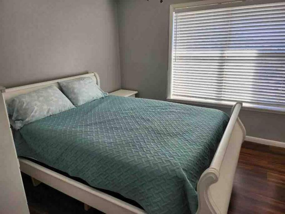 a bedroom with a bed with a green comforter and a window at Lovely Condo on the Water in Kemah