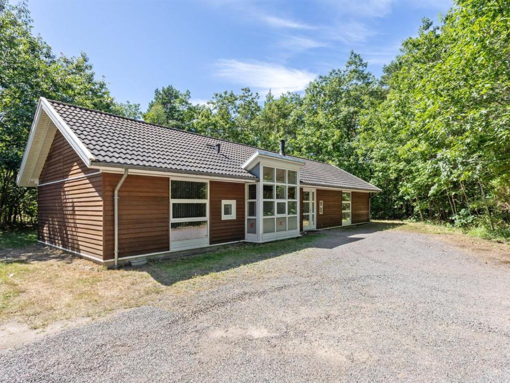 a small cabin with a driveway in front of some trees at Holiday Home Dafne - 600m from the sea in Bornholm by Interhome in Hasle