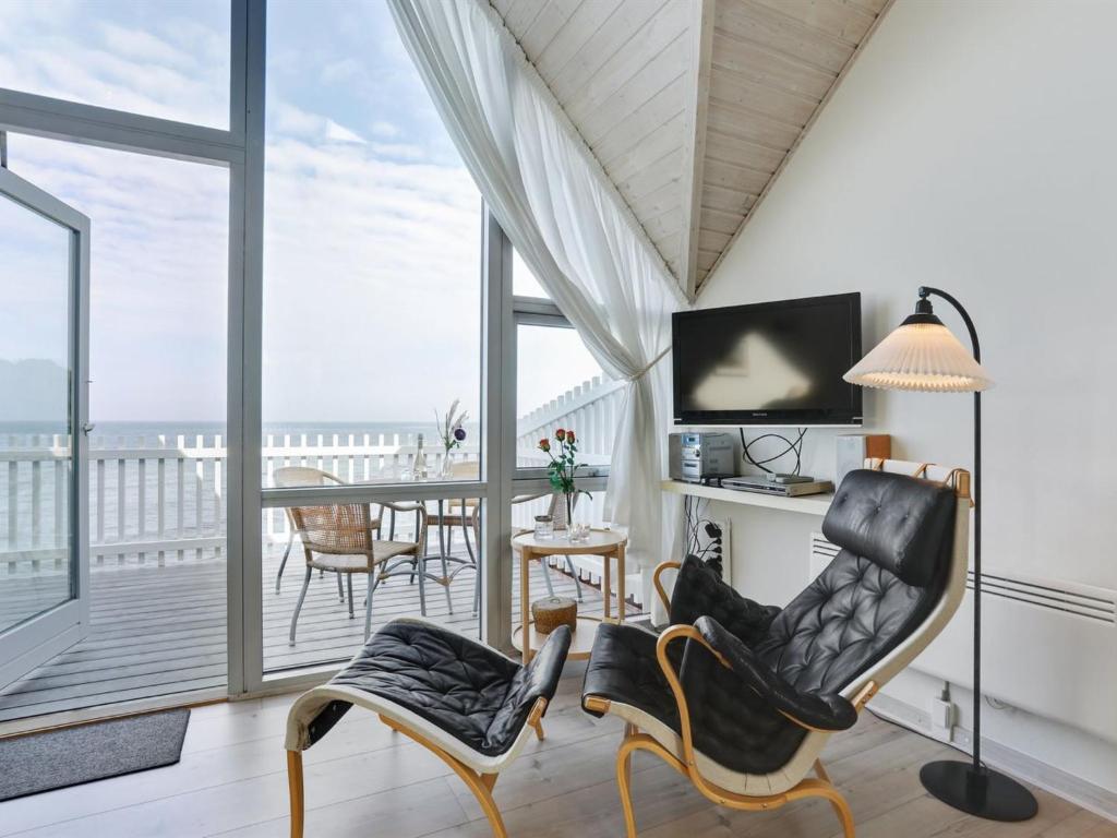 a living room with a balcony with a table and chairs at Holiday Home Momo - 10m from the sea in Bornholm by Interhome in Hasle