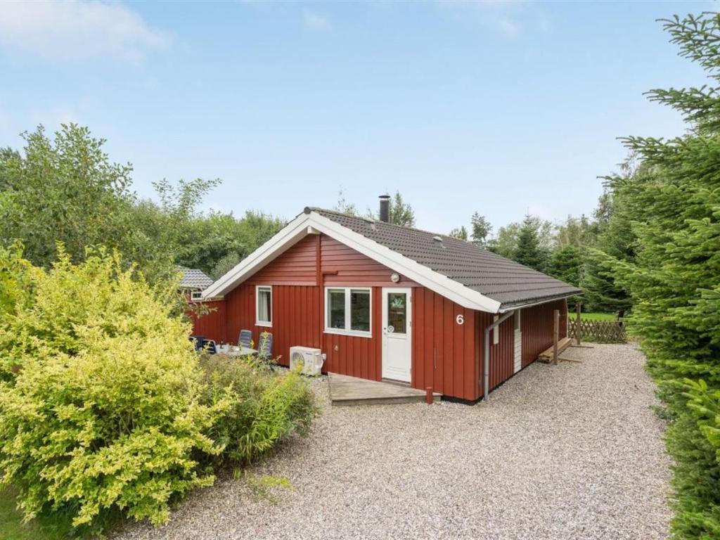 une cabine rouge avec une véranda et des arbres dans l'établissement Holiday Home Lyra - 800m from the sea in Lolland- Falster and Mon by Interhome, à Bøtø By