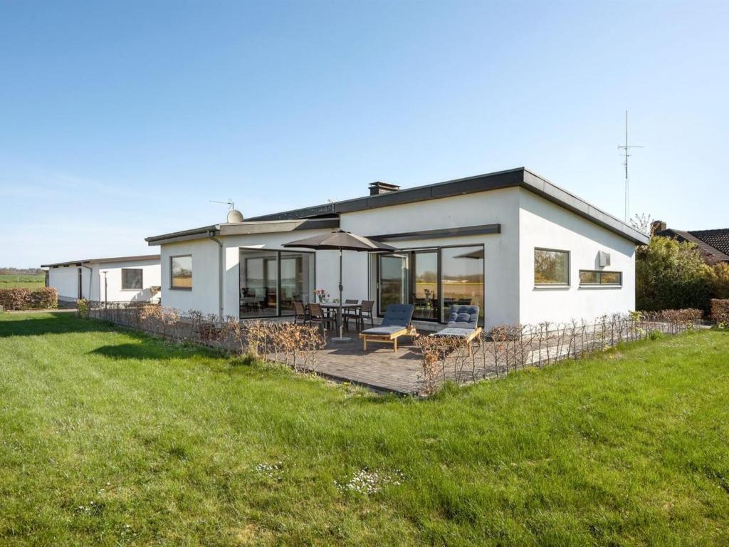 ein weißes Haus mit einer Terrasse und einer Liegewiese in der Unterkunft Holiday Home Ermelinda - 900m to the inlet in SE Jutland by Interhome in Nordborg