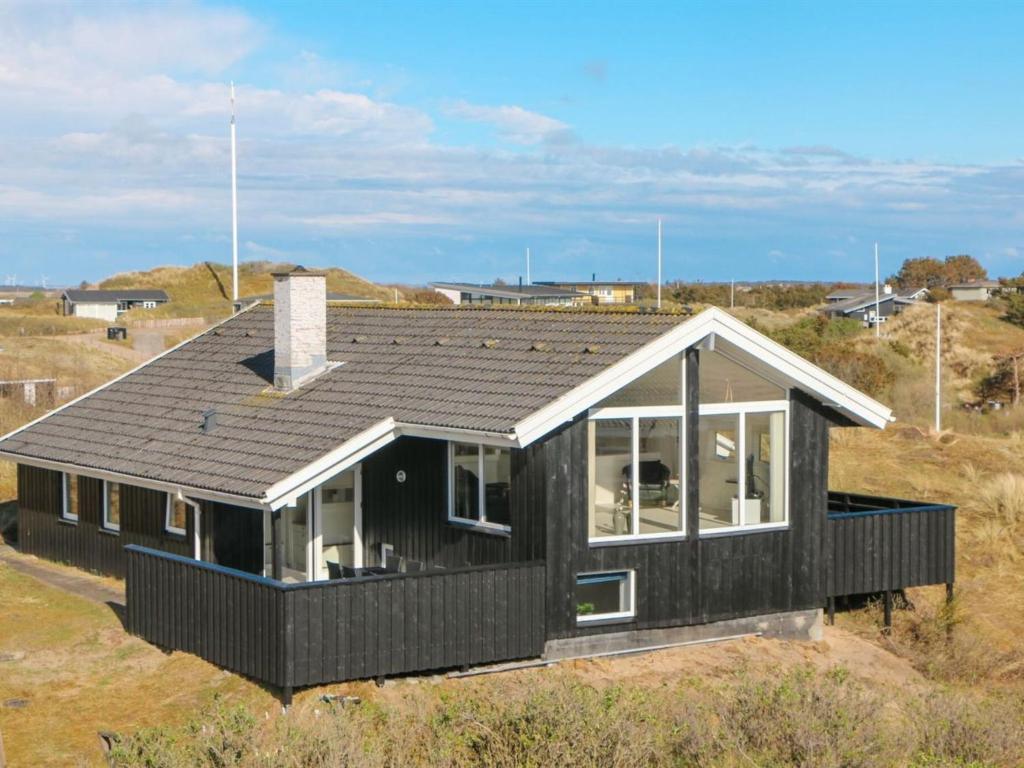 uma casa negra no topo de um campo em Holiday Home Hansina - 500m from the sea in Western Jutland by Interhome em Fanø