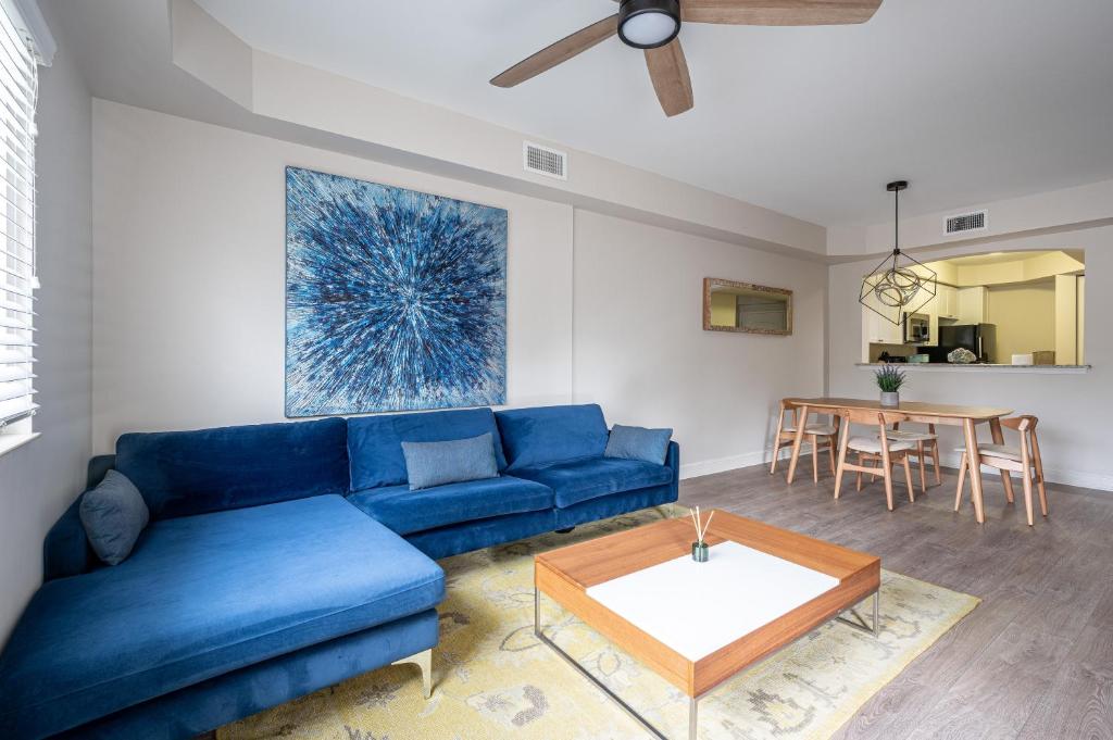 a living room with a blue couch and a table at Updated Beach Condo! Facing Heated Pool & Sunset! in Naples