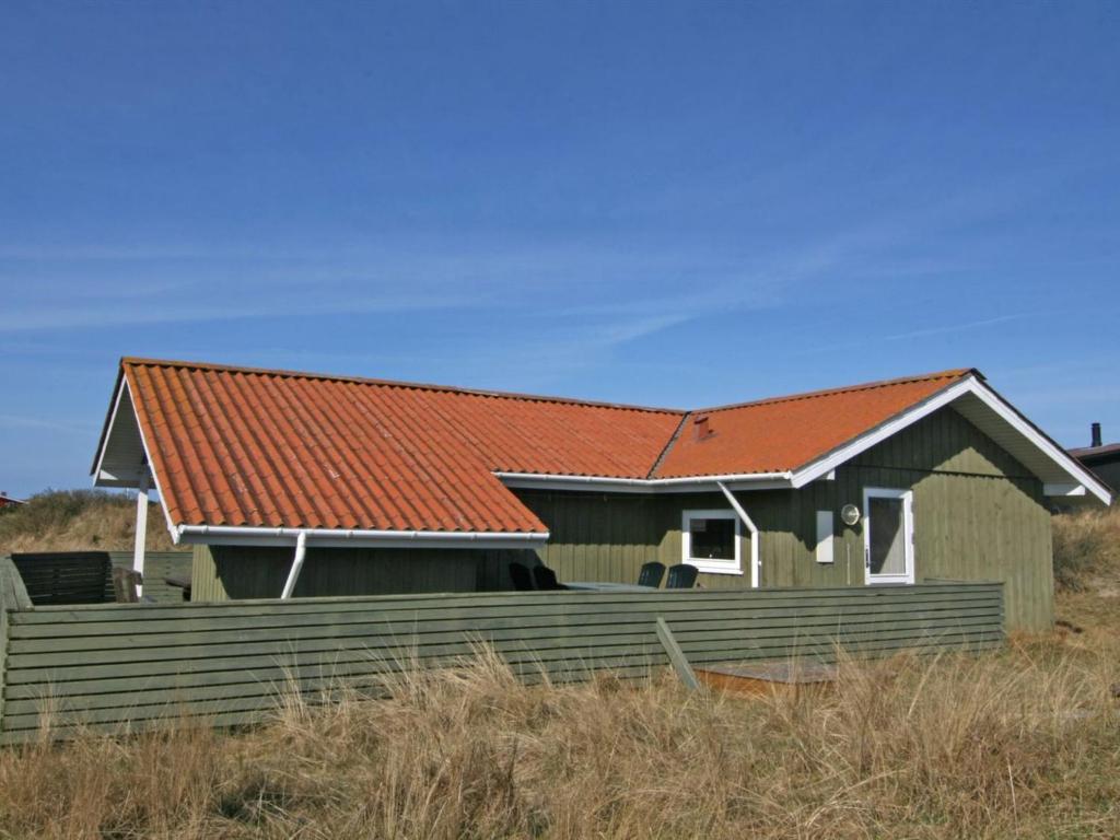 ein Haus mit rotem Dach und einem Zaun in der Unterkunft Holiday Home Aasa - 200m from the sea in Western Jutland by Interhome in Fanø
