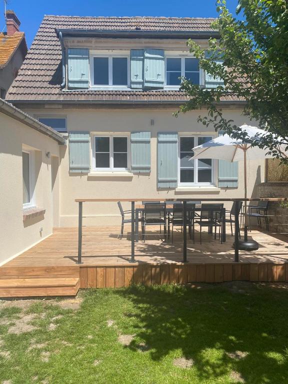 une terrasse avec des tables et des parasols en face d'une maison dans l'établissement Maison cosy en plein coeur de Ouistreham, à Ouistreham