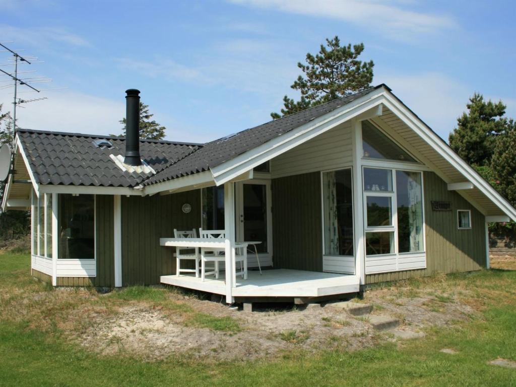 una pequeña casa verde con porche y mesa en Holiday Home Klint - 1-7km from the sea in Western Jutland by Interhome, en Fanø