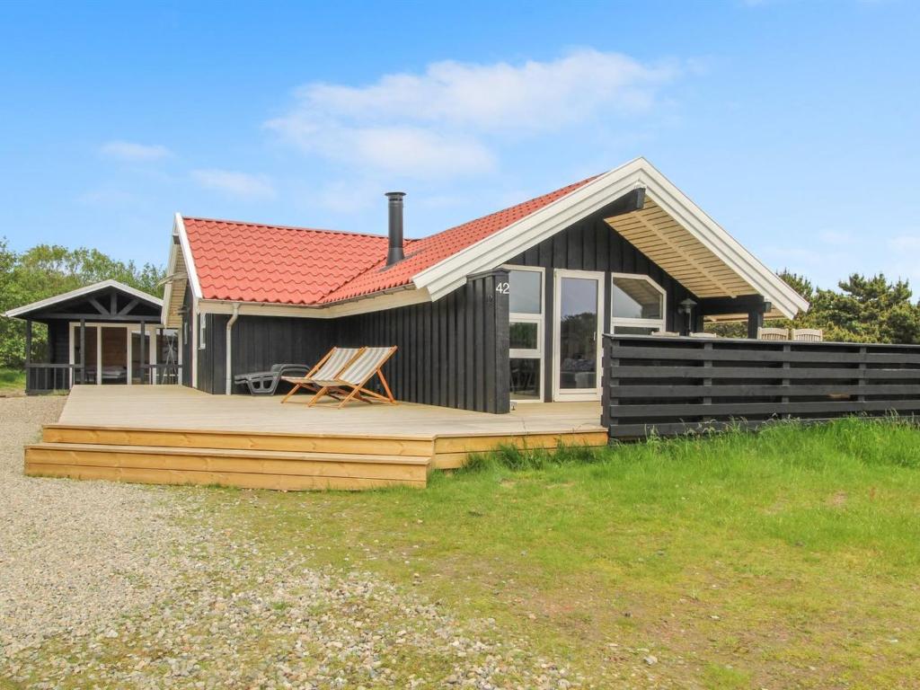 een klein huis met een terras en een dak bij Holiday Home Skyler - 1km from the sea in Western Jutland by Interhome in Fanø