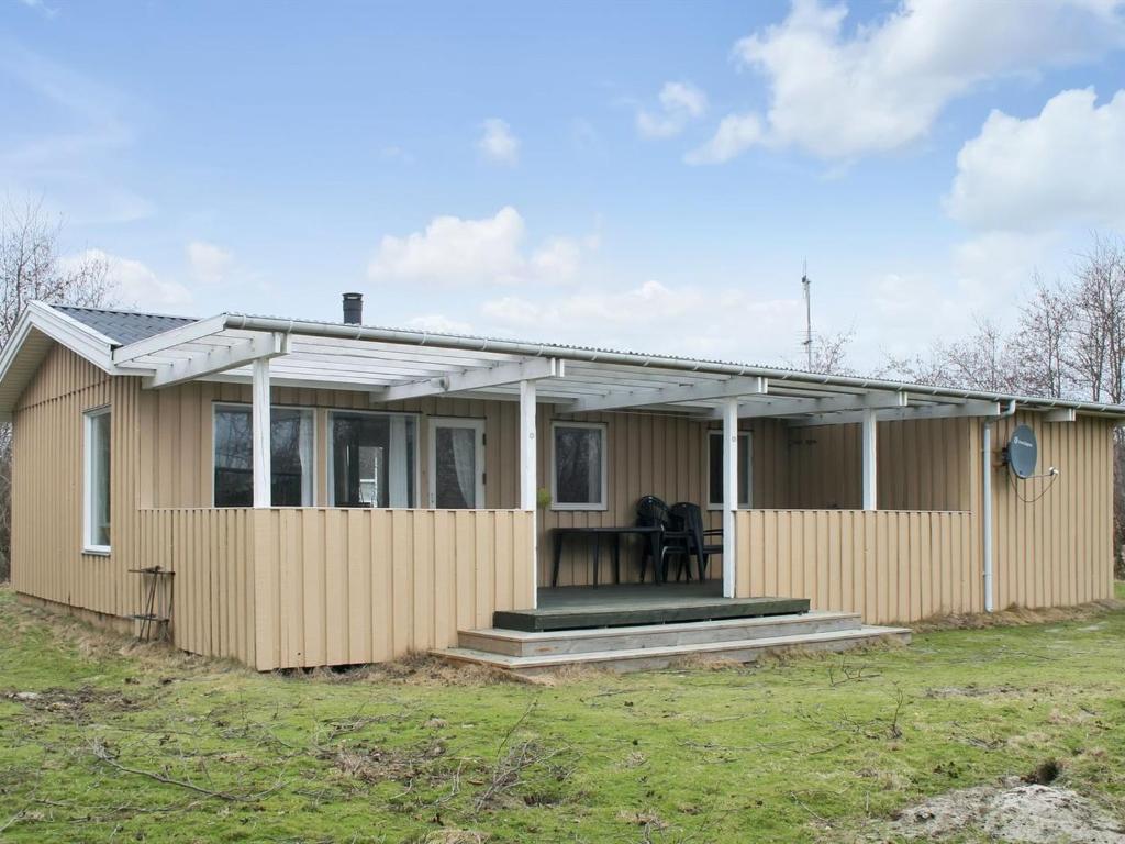 a small house with a porch on a field at Holiday Home Svanhild - 1-2km from the sea in Western Jutland by Interhome in Fanø