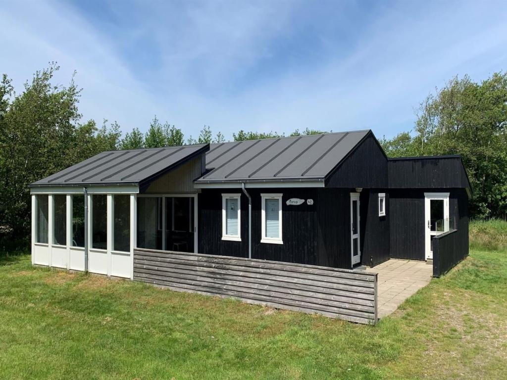 een zwart huis met een terras in een veld bij Holiday Home Patrice - 2km from the sea in Western Jutland by Interhome in Fanø