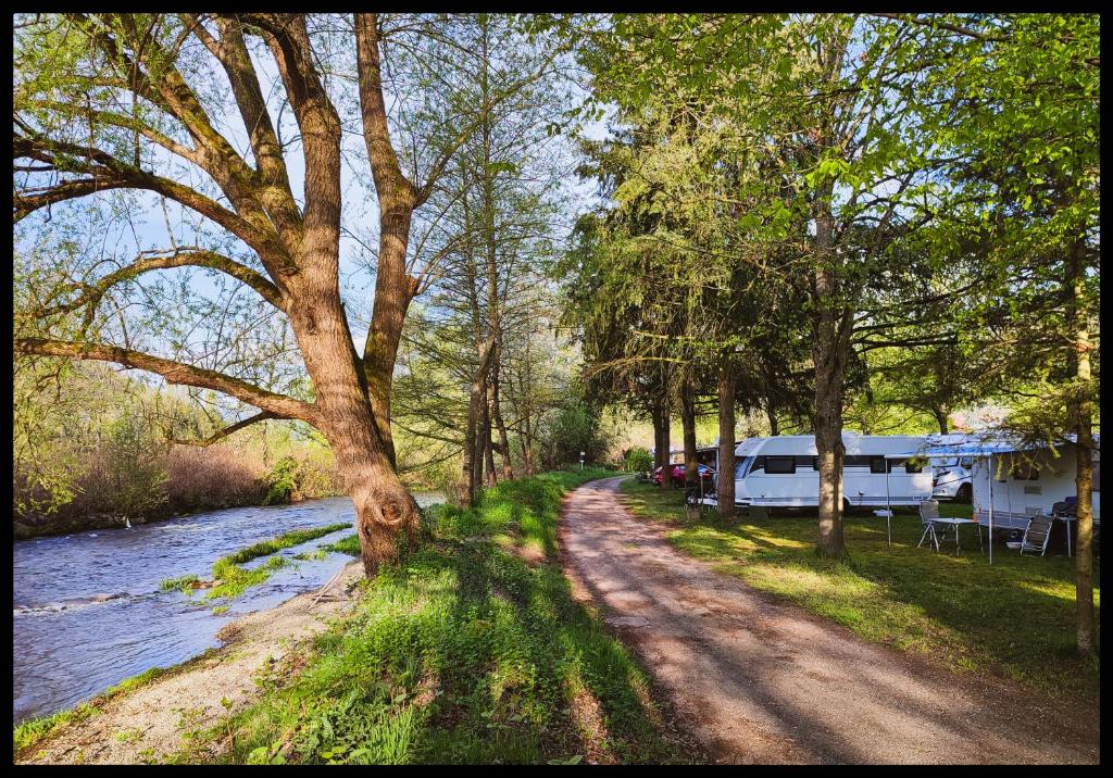 a dirt road next to a river with a rv at Mobil-home Beau Rivage in Gunsbach