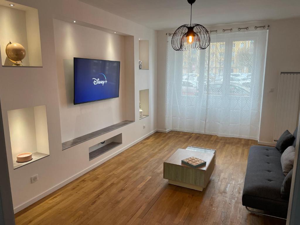 a living room with a couch and a tv on a wall at Appartement du lion in Belfort