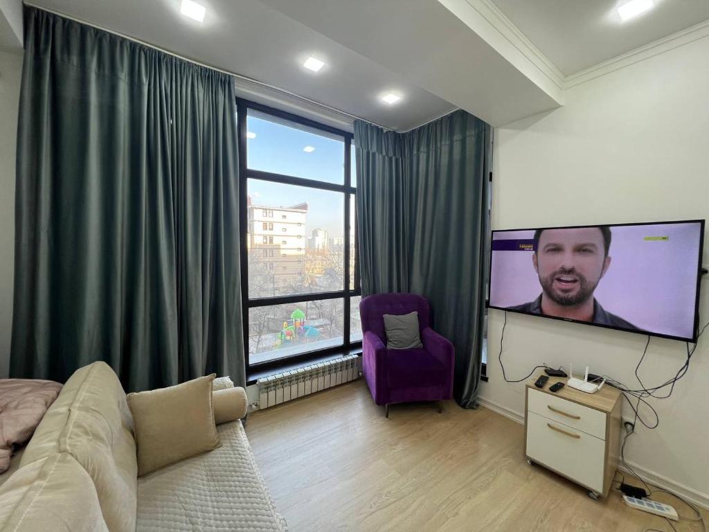 ein Schlafzimmer mit einem großen Bildschirm mit einem Mann drauf in der Unterkunft 2-room apartment Centrium Residence in Bischkek