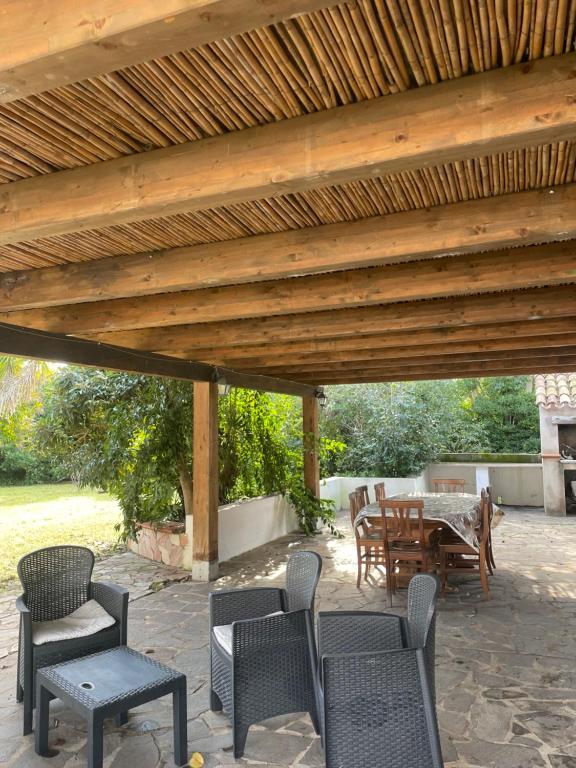 un patio con mesa y sillas bajo una pérgola de madera en Roy House, en Alghero