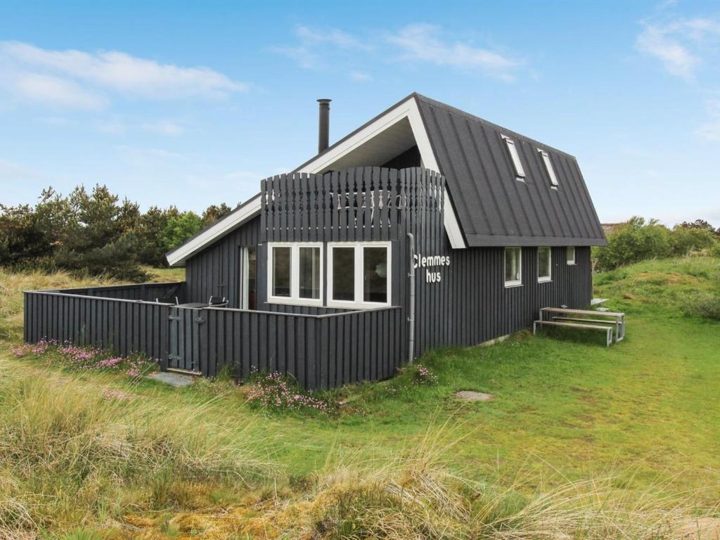 a black house sitting on top of a grass field at Holiday Home Casandra - 600m from the sea in Western Jutland by Interhome in Fanø