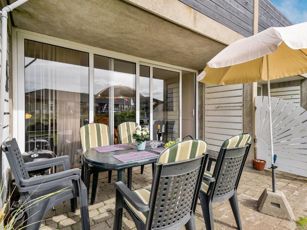 un tavolo con sedie e un ombrellone su un patio di Apartment Iliane - 100m from the sea in Western Jutland by Interhome a Fanø