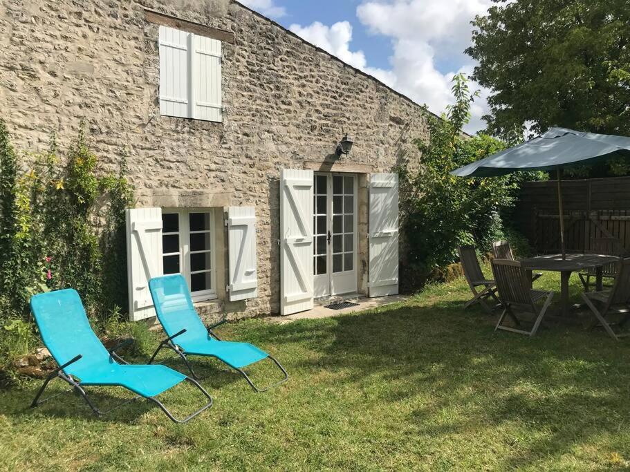 duas cadeiras e uma mesa e um guarda-sol num quintal em Maison de village et jardin , à Mornac sur Seudre em Mornac-sur-Seudre