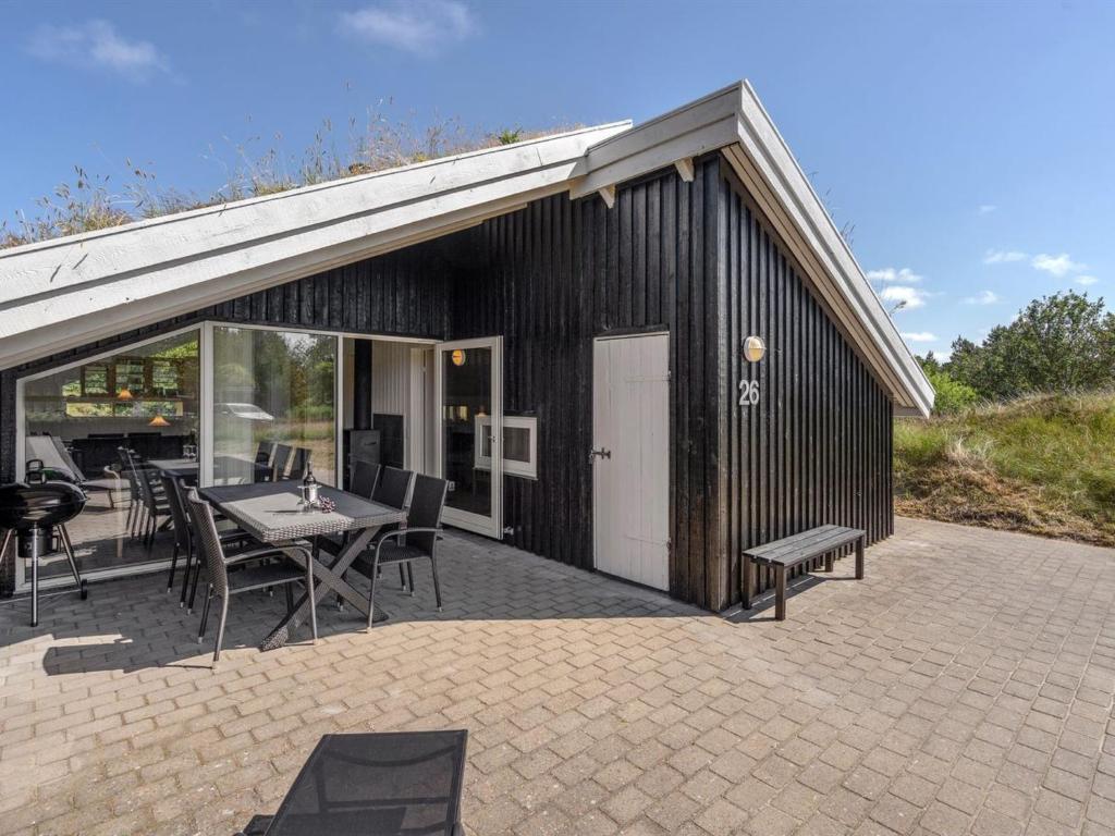 een gebouw met een patio met een tafel en stoelen bij Holiday Home Thera - 2-8km from the sea in Western Jutland by Interhome in Bolilmark