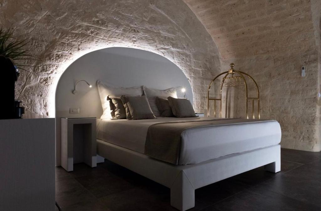 una camera con un letto bianco su un muro di pietra di The Saint stays a Bari