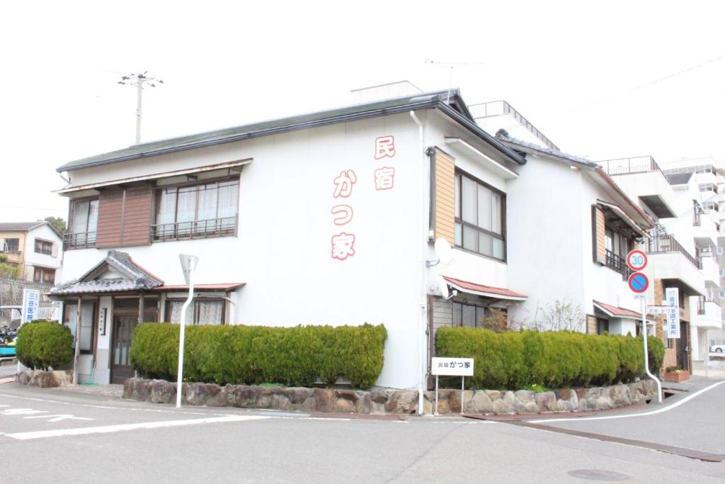 a white building on the corner of a street at Minshuku Katsuya in Shirahama