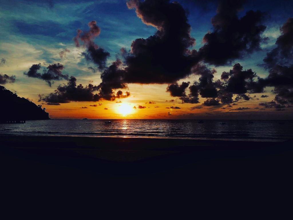 a sunset on a beach with the ocean at Tiongman Scubadive & Lodge in Tioman Island