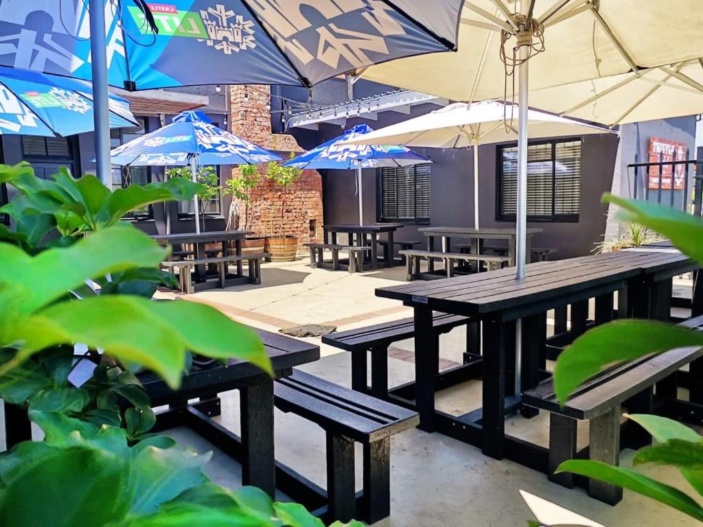grupa stołów piknikowych i parasoli na patio w obiekcie Thistle Hotel w mieście Pietermaritzburg