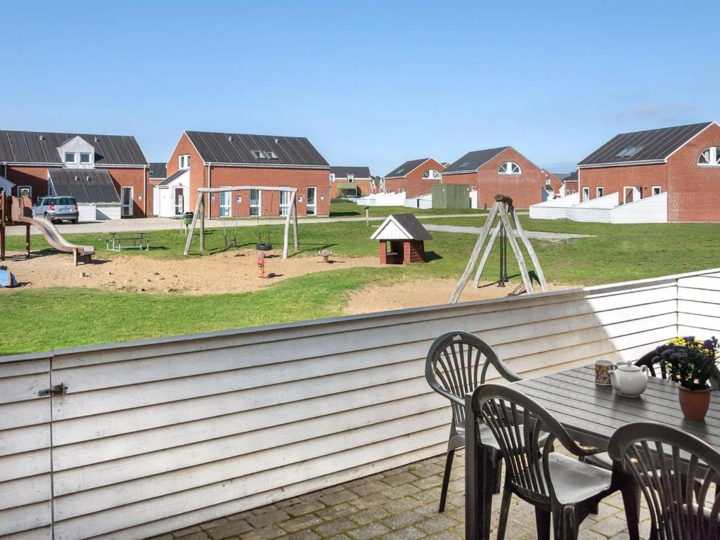 eine Terrasse mit einem Tisch und Stühlen sowie einem Spielplatz in der Unterkunft Apartment Odger - 2-3km from the sea in Western Jutland by Interhome in Sønderby