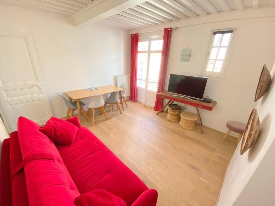 un soggiorno con un divano rosso e un tavolo di Plein centre trouville, 200m de la plage, 2/4 pers a Trouville-sur-Mer