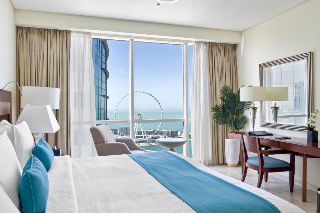 a hotel room with a bed and a desk and a view at Blue Beach Tower The Walk JBR in Dubai