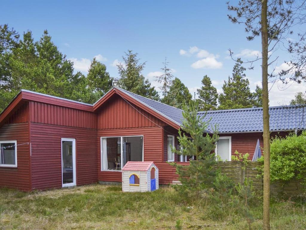a red house with a dog house in front of it at Holiday Home Dorreth - 800m from the sea in Western Jutland by Interhome in Mølby