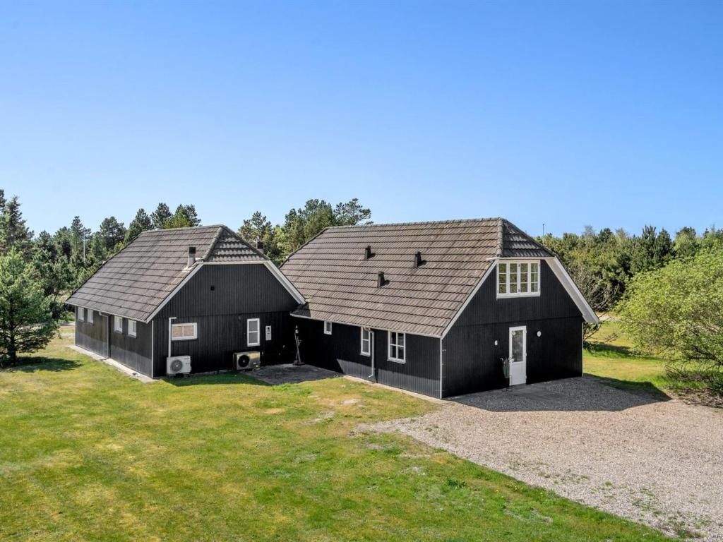 two black barns with white doors on a field at Holiday Home Madalena - 2-8km from the sea in Western Jutland in Toftum